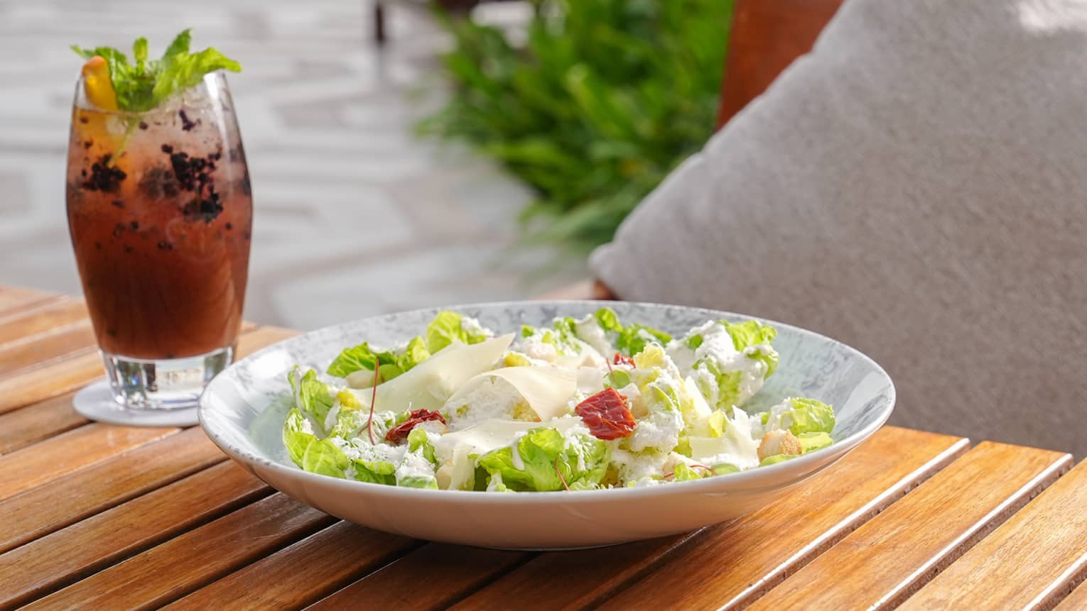 A salad next to a cocktail.