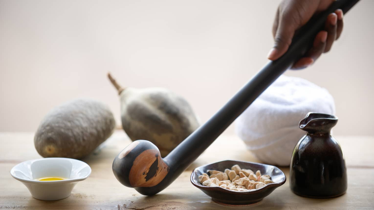 Hand holds wood warrior baton near small bowls, large nuts