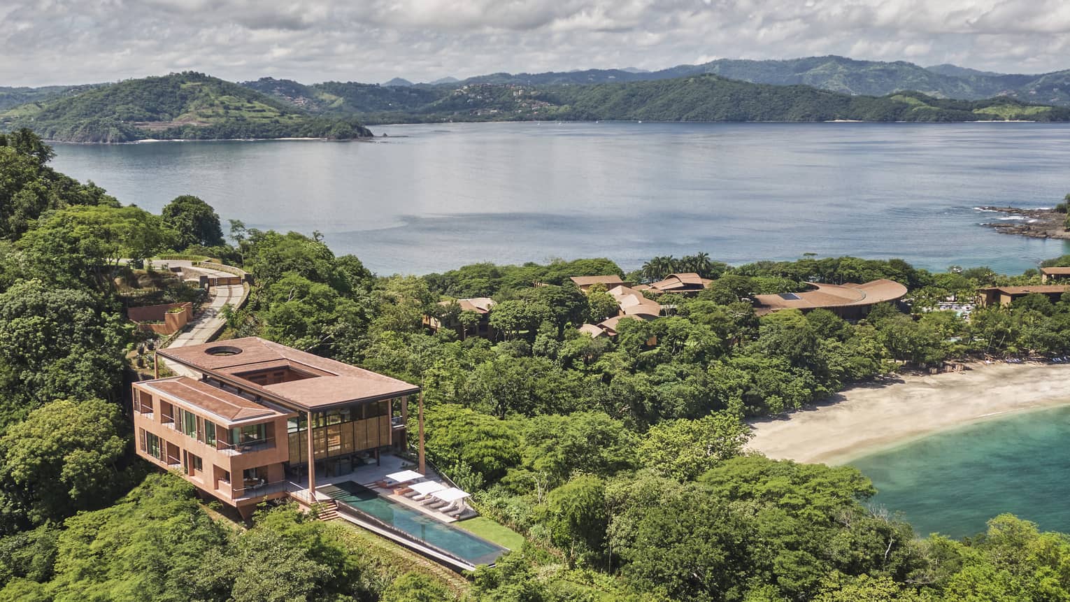 Aerial view of private villa with long rectangular pool near a beach
