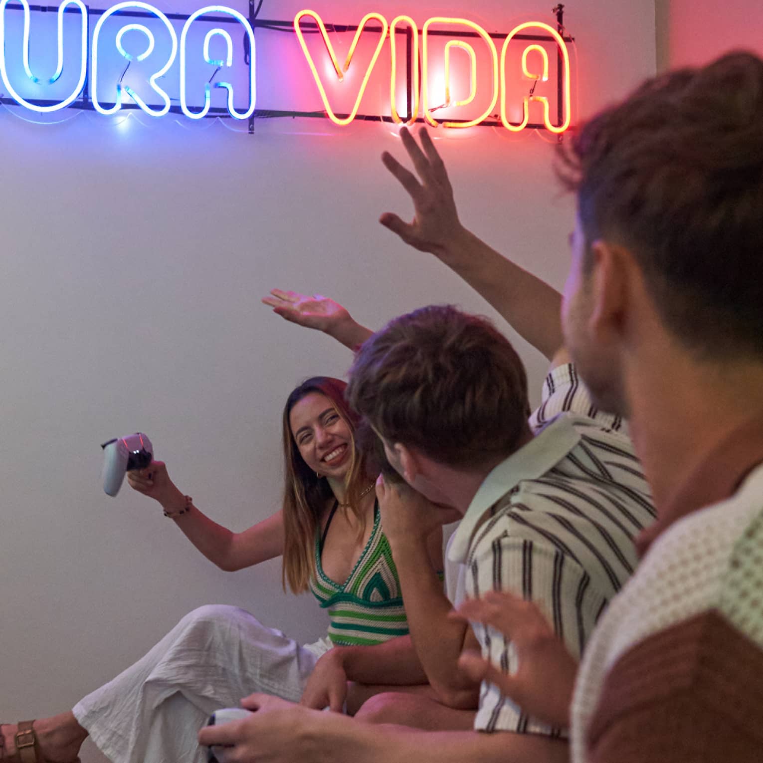 Teens sit on a couch smiling and playing games