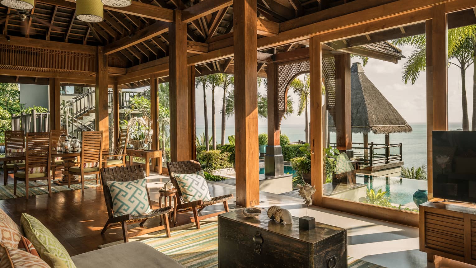 Bright, open air living and dining room, seats under rustic wood beam ceilings