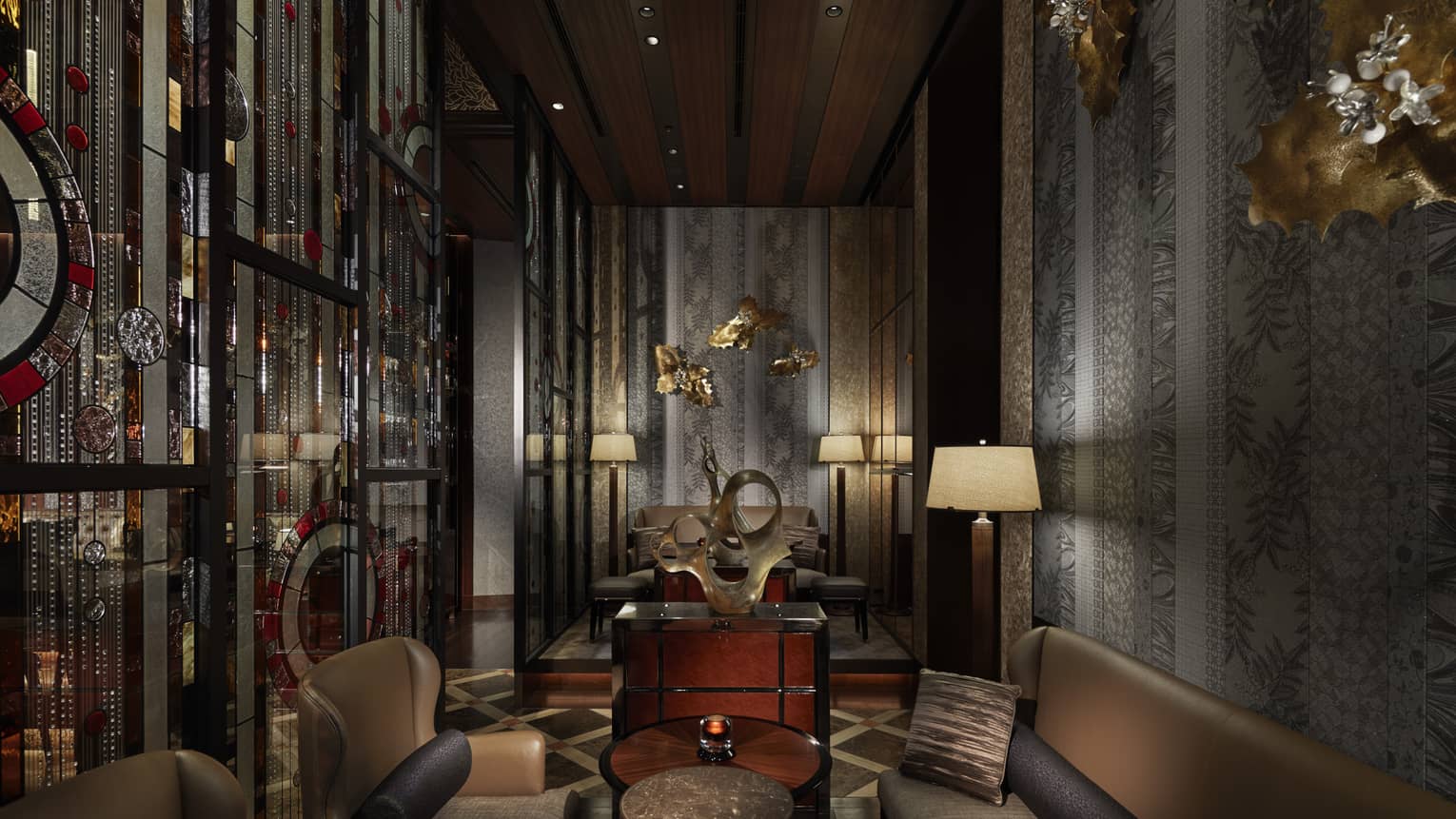 Private lounge area with leather chairs and couch, muted tones, gold wall decor 