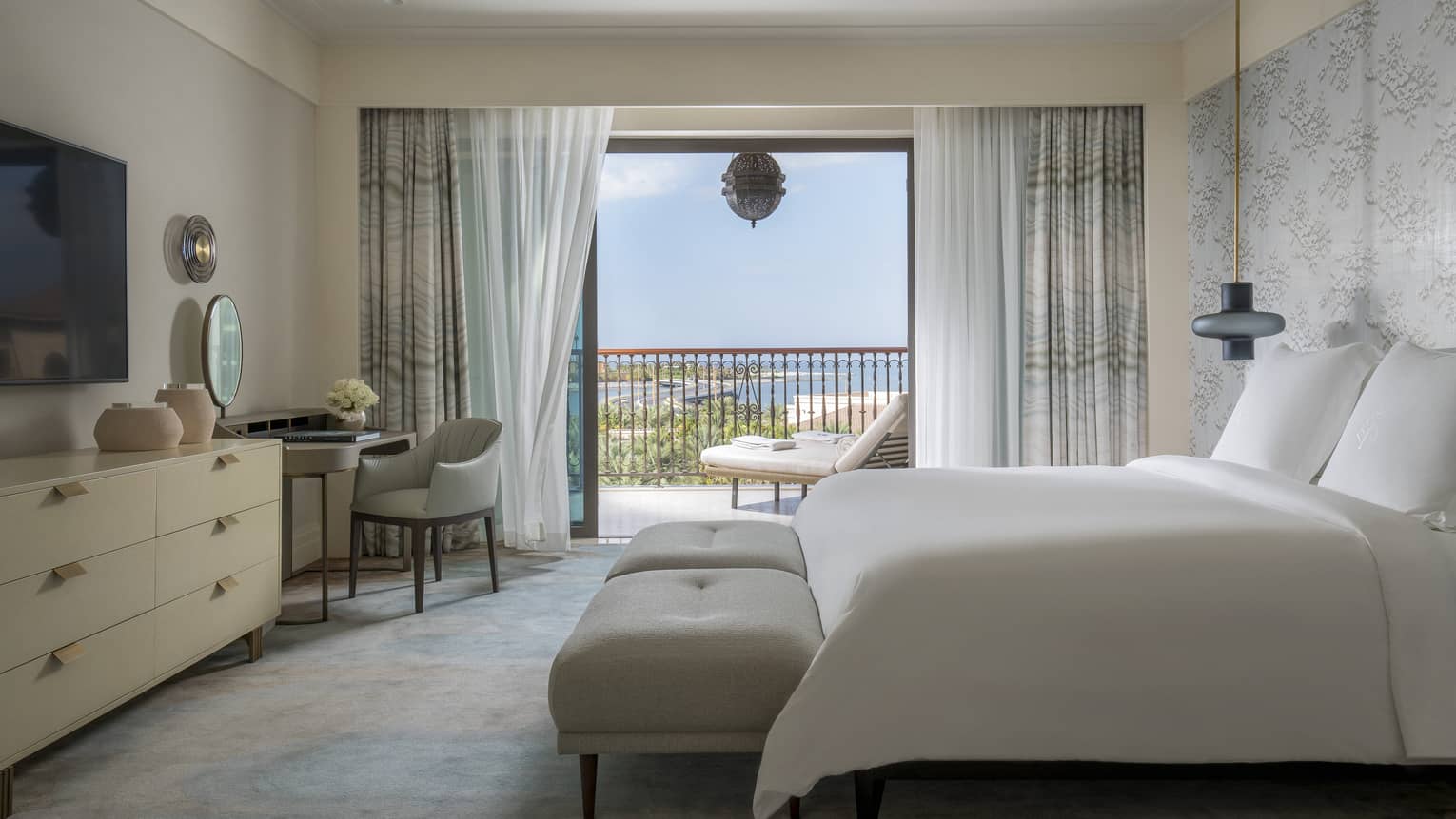 A large white bed sits in the centre of a spacious suite overlooking the Persian Gulf.