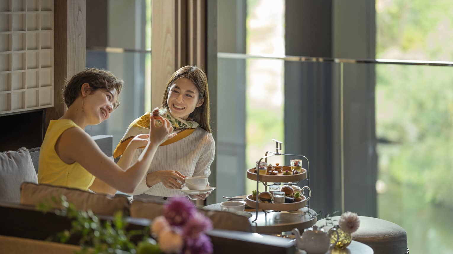 Two laughing women enjoy afternoon tea at The Lounge 