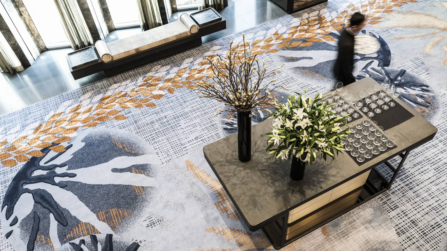 Aerial view of man walking past table with wine glasses and flowers in Nuri Ballroom Foyer