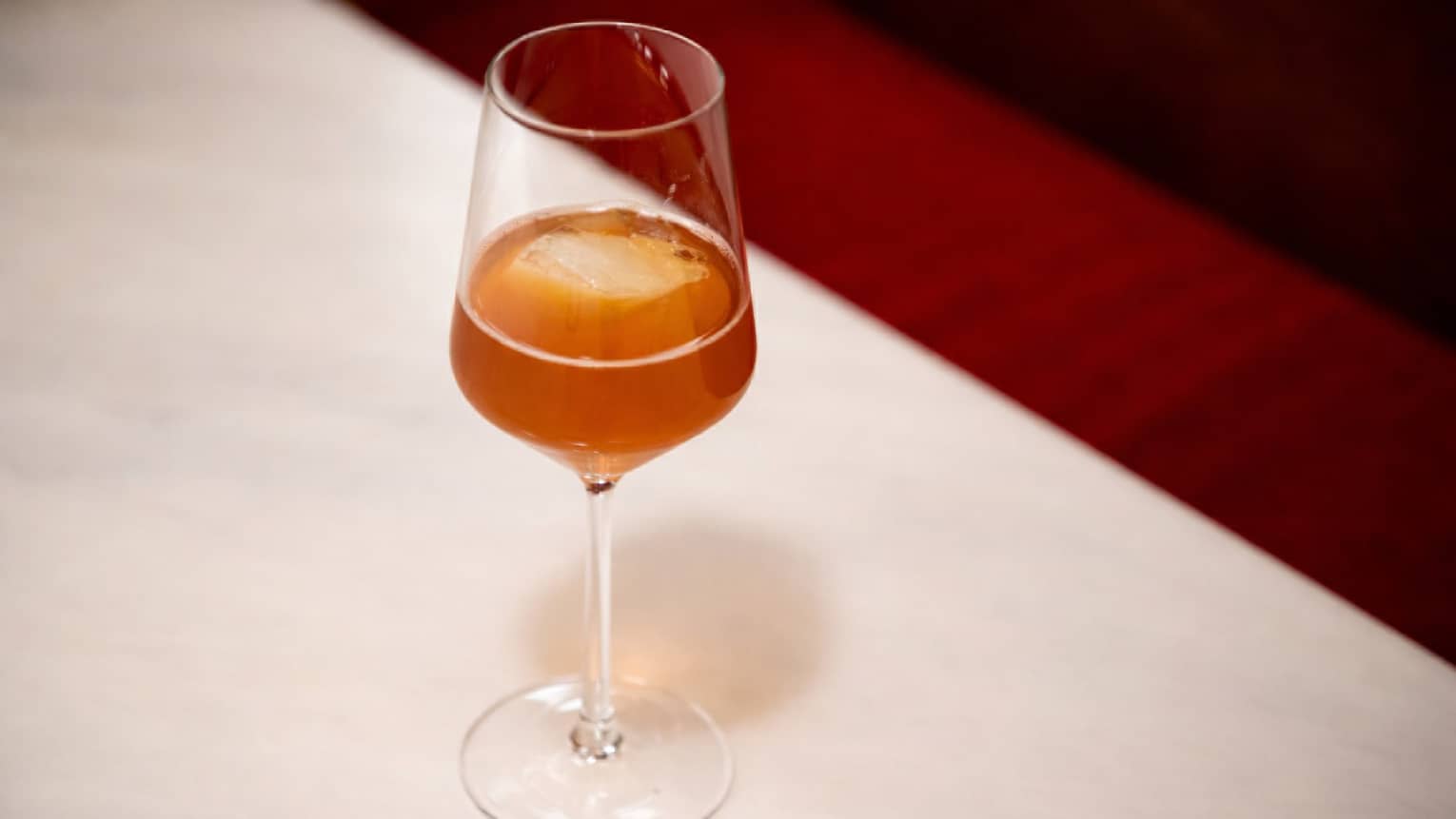 A dark amber cocktail in a slender stemmed glass