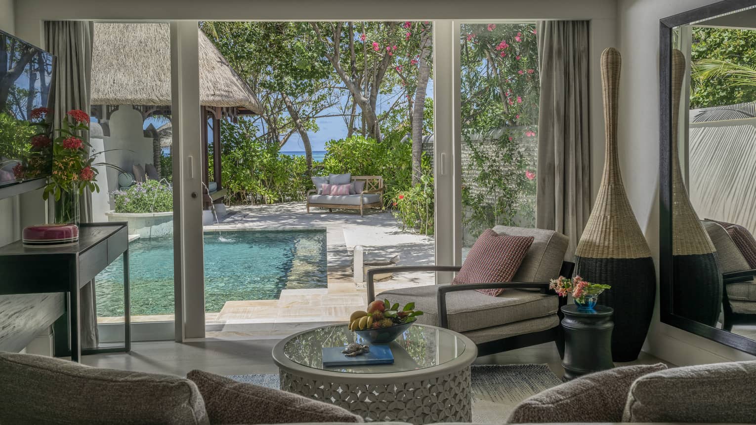 Living room opening to pool deck, with beach in the distance