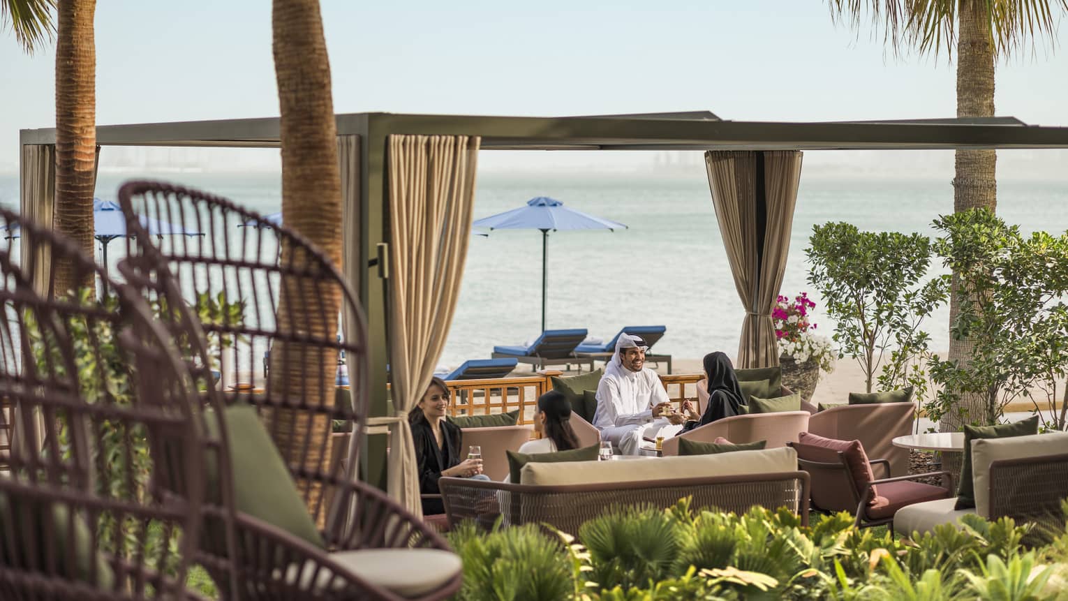 People sitting by the beach in an outdoor seating area in luxury hotel