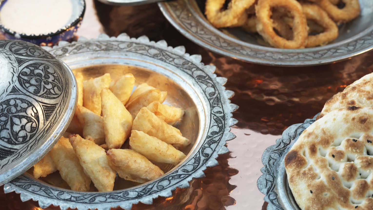 Close-up of breaded fried foods, bread in silver dishes 