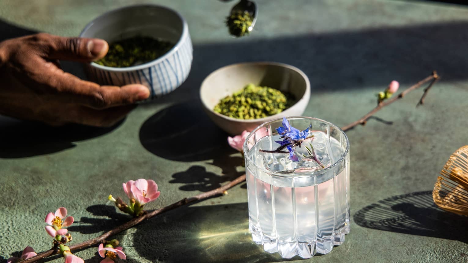 A clear cocktail with lavender as a garnish.