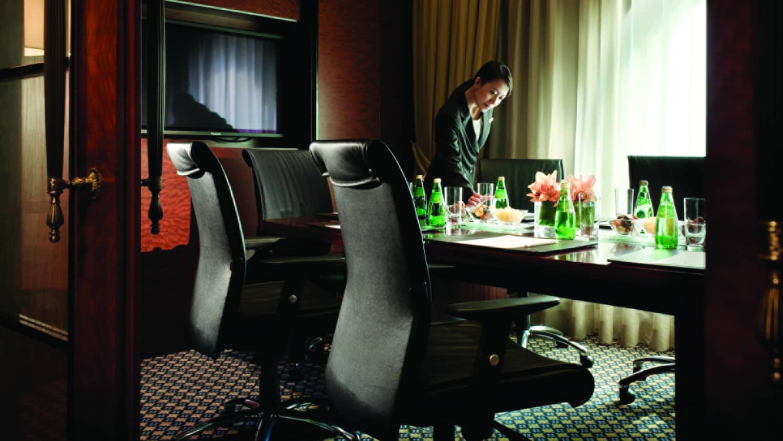 Woman sets water glass on Executive Lounge Meeting Room boardroom table