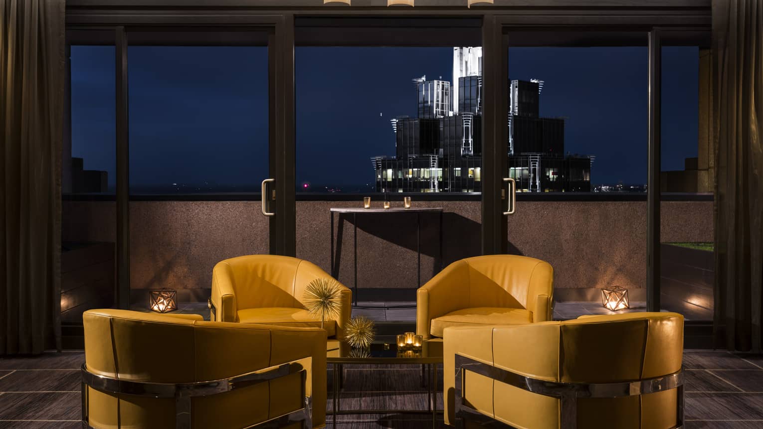 Yellow leather lounge chairs at dusk, the cityscape in the background 