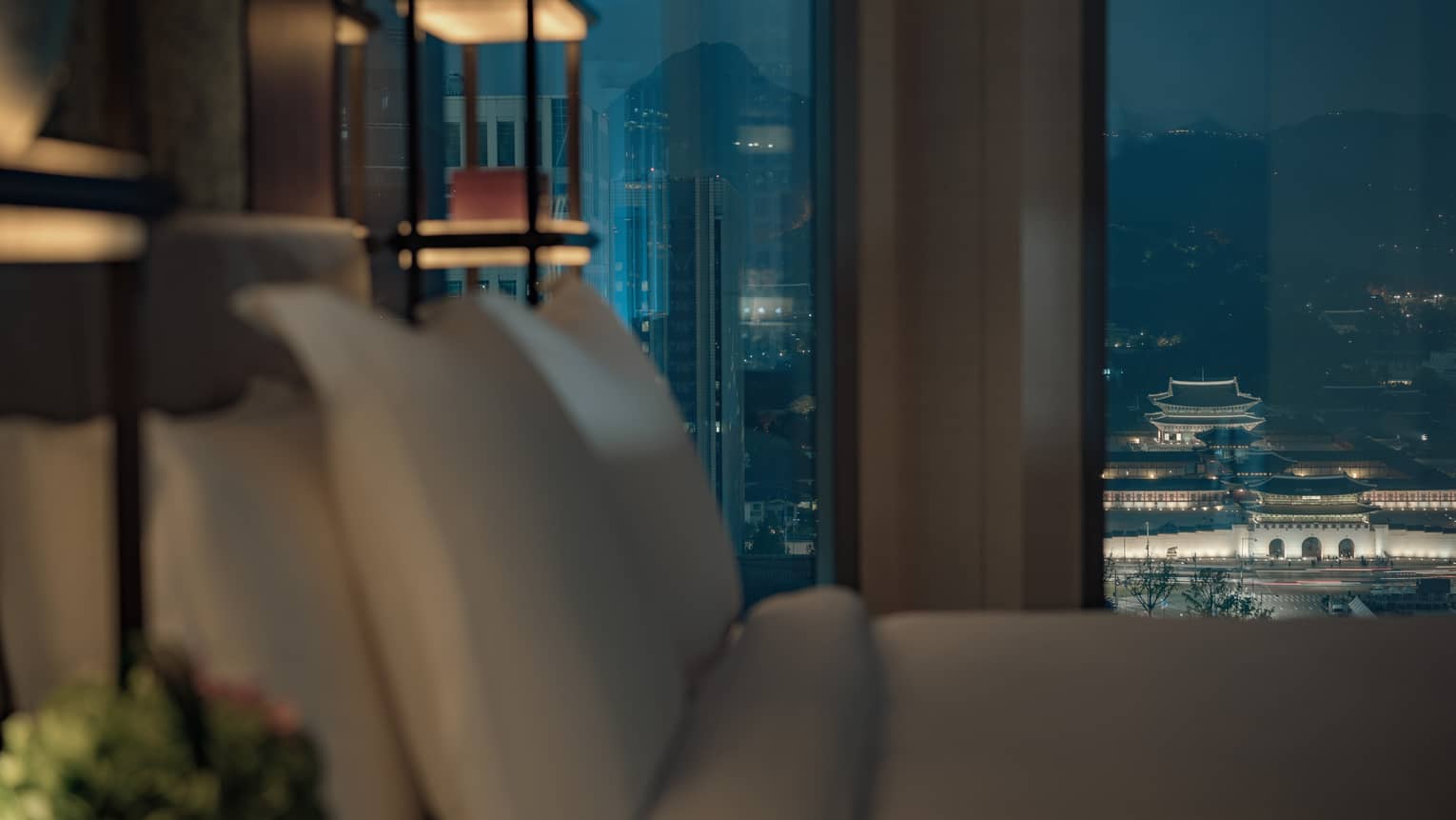 Palace-View Executive Suite close-up of hotel bed pillows in front of large window at night, city lights