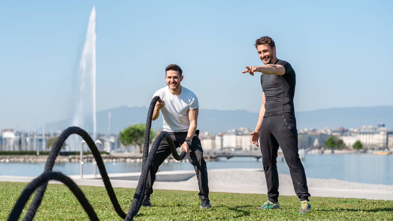 Man working out with ropes with guidance of trainer at Lake Geneva grassy shore