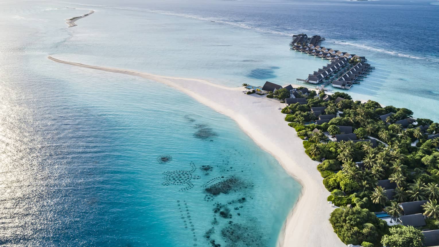 This image depicts a white sand beach, lush greenery and turquoise blue water at the beautiful Four Seasons Resort Maldives at Landaa Giraavaru – home to many outstanding ESG initiatives.