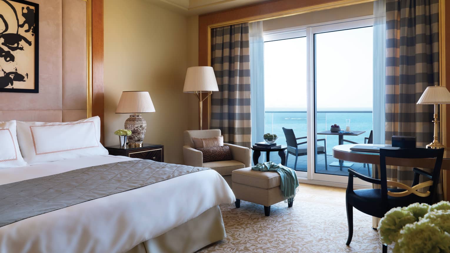 Premium Room with king size bed, armchair and plush ottoman beside patio door with blue checkered curtains