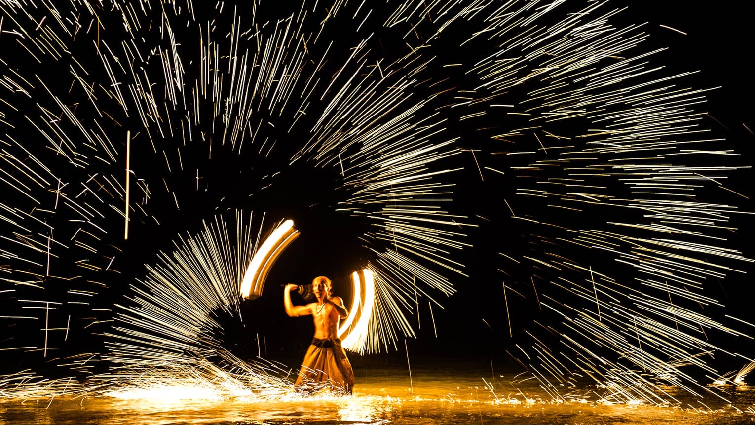 Streaks of light around man spinning fire 