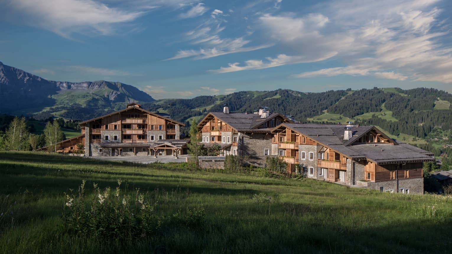 Four Seasons Hotel Mègeve rustic ski resort at edge of meadow, mountains