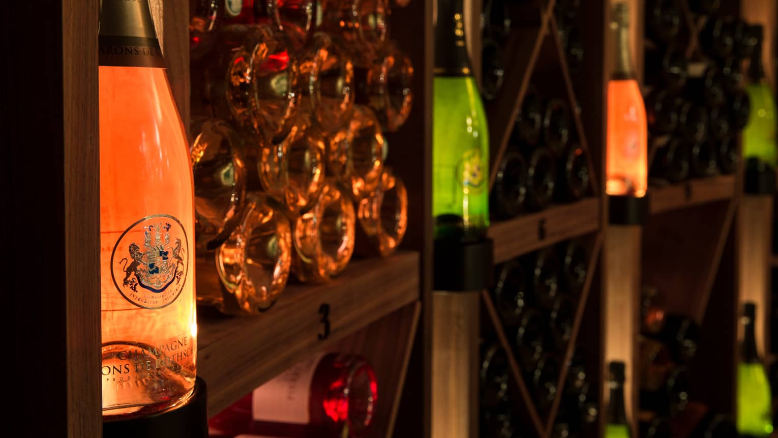 Close-up of wine cellar shelves with some bottles stacked, others on display with lights