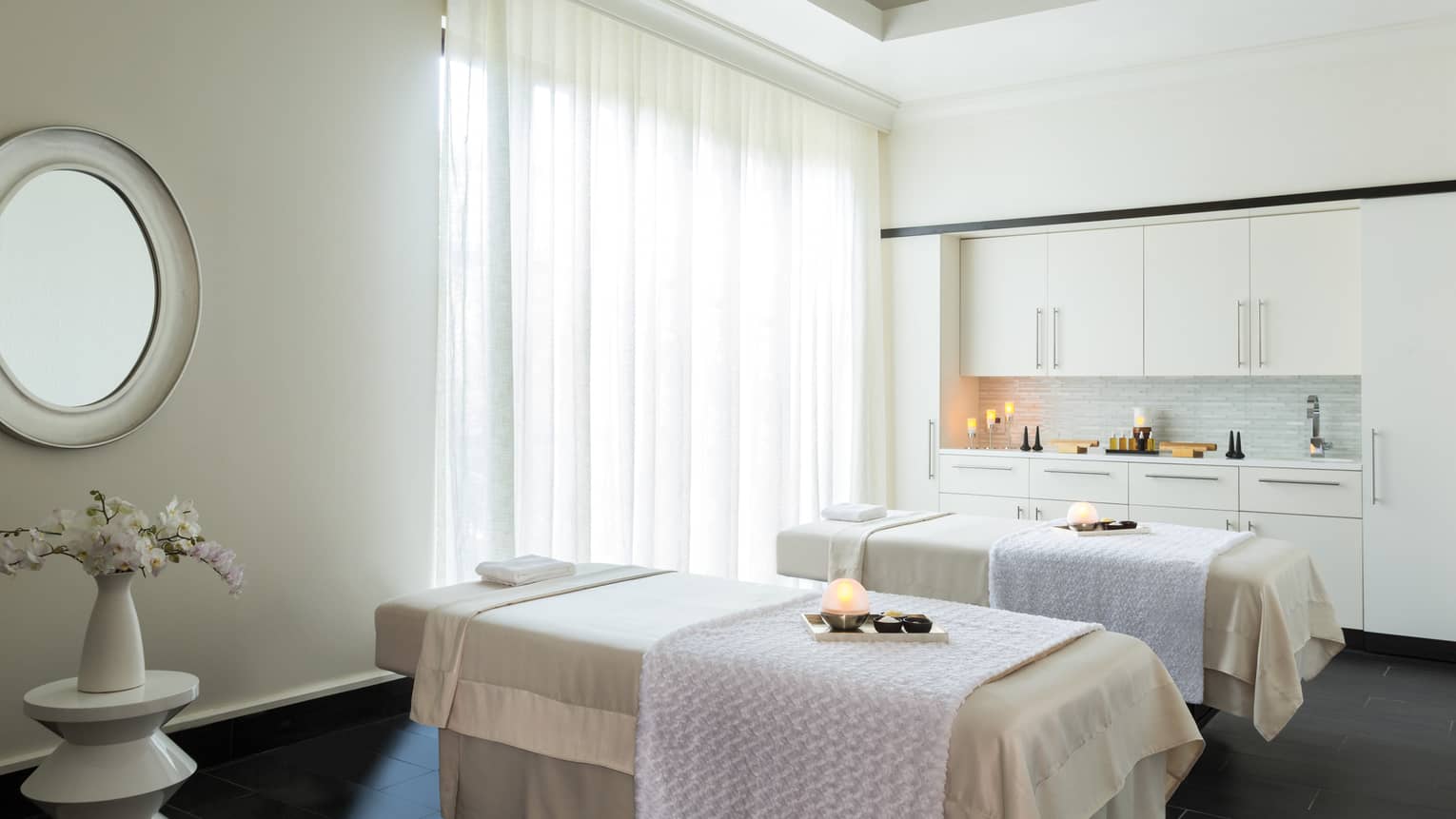 Couples Suite two massage tables with trays with glowing candles, salts in spa treatment room