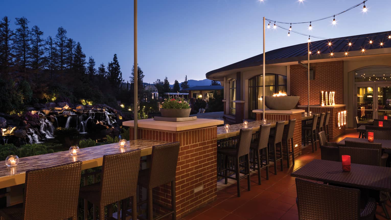 Candle-lit bar, stools along Lookout patio, string of lights, outdoor patio, waterfall views