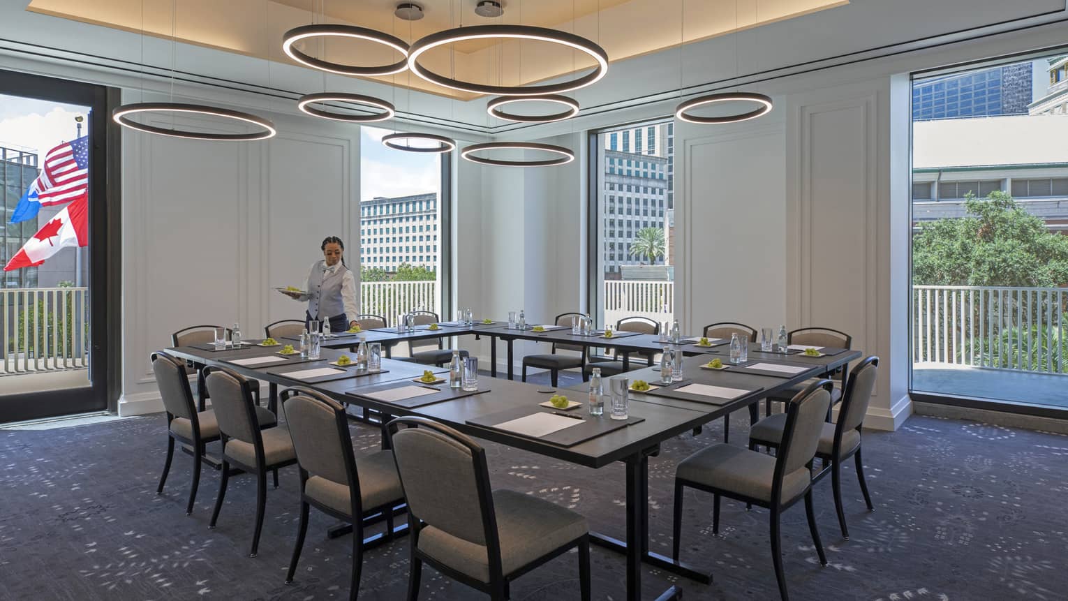 Meeting room with u-shaped table set for twelve, floor-to-ceiling windows, natural light, circular hanging decor