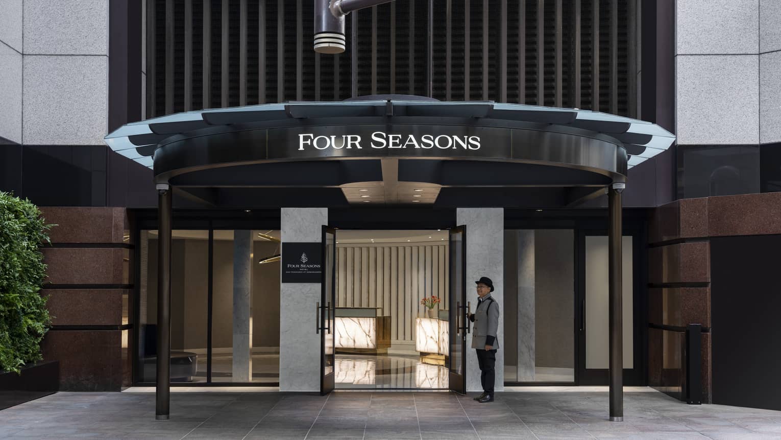 An entrance to a hotel with a team member standing at the door.