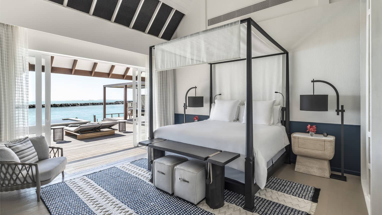 Bedroom with four-poster canopied bed with doorway leading to pool deck with cabana
