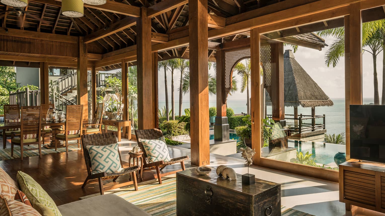 Bright, open air living and dining room, seats under rustic wood beam ceilings