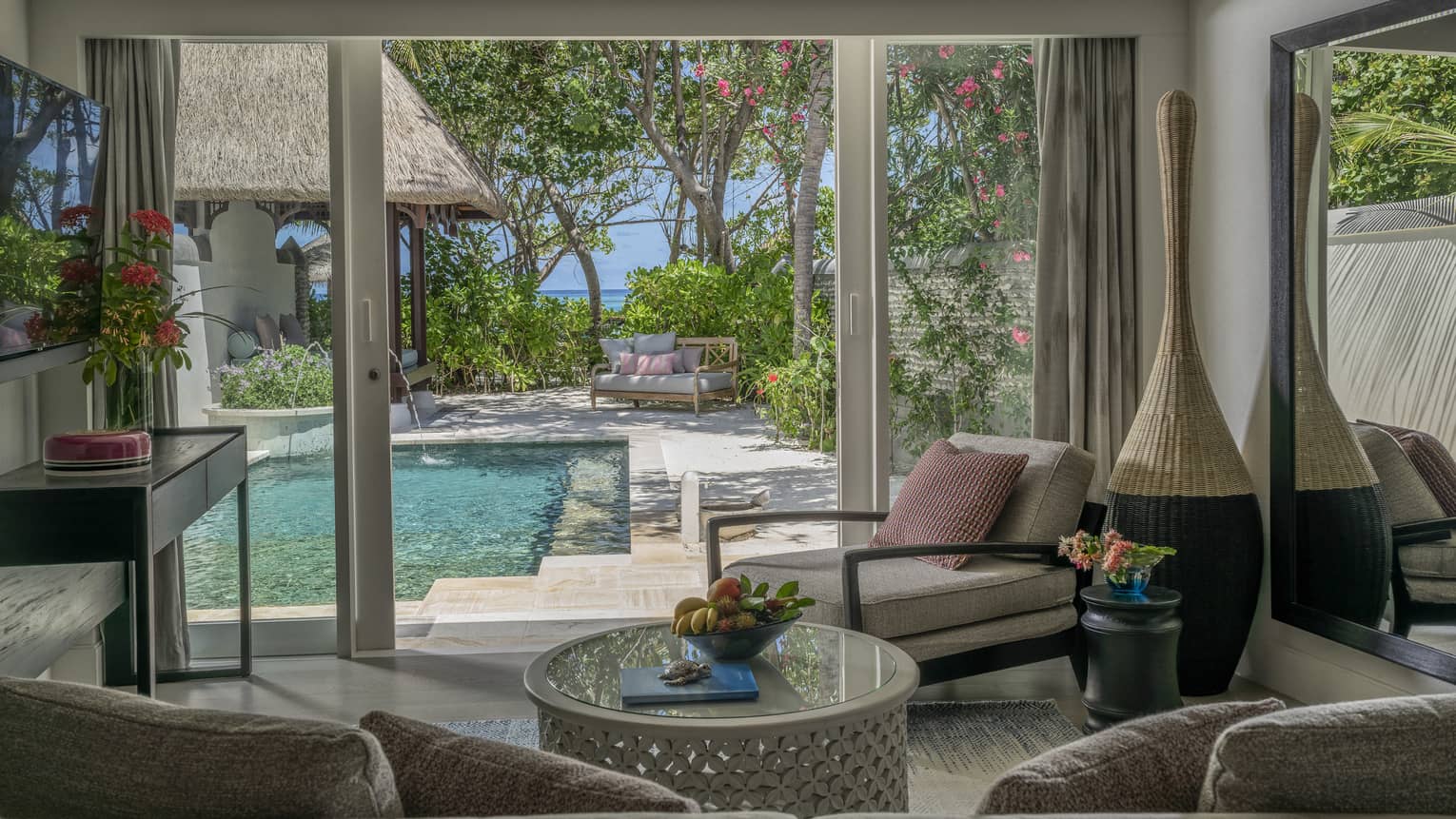 Living room opening to pool deck, with beach in the distance