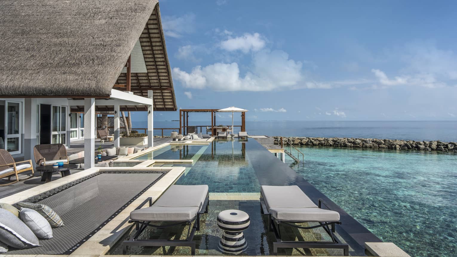 Private pool deck of overwater villa, with overwater lounge net and two chairs