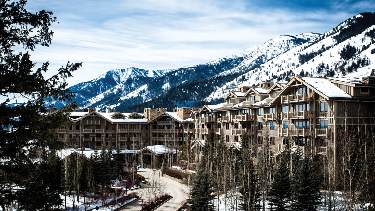 the exterior of the hotel is covered in snow and surrounded by snow capped mountains 