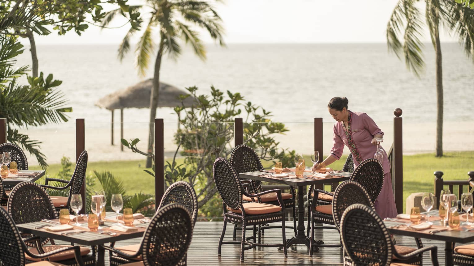 A hostess completing a table setting on the al-fresco terrace of Four Seasons’ Ikan-Ikan restaurant in Langkawi. 