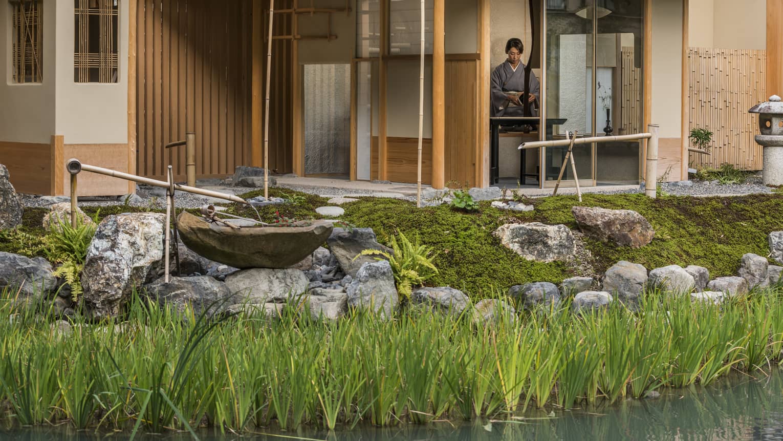Rock garden, fountain in front of Shakusui tei building, woman in robe behind window
