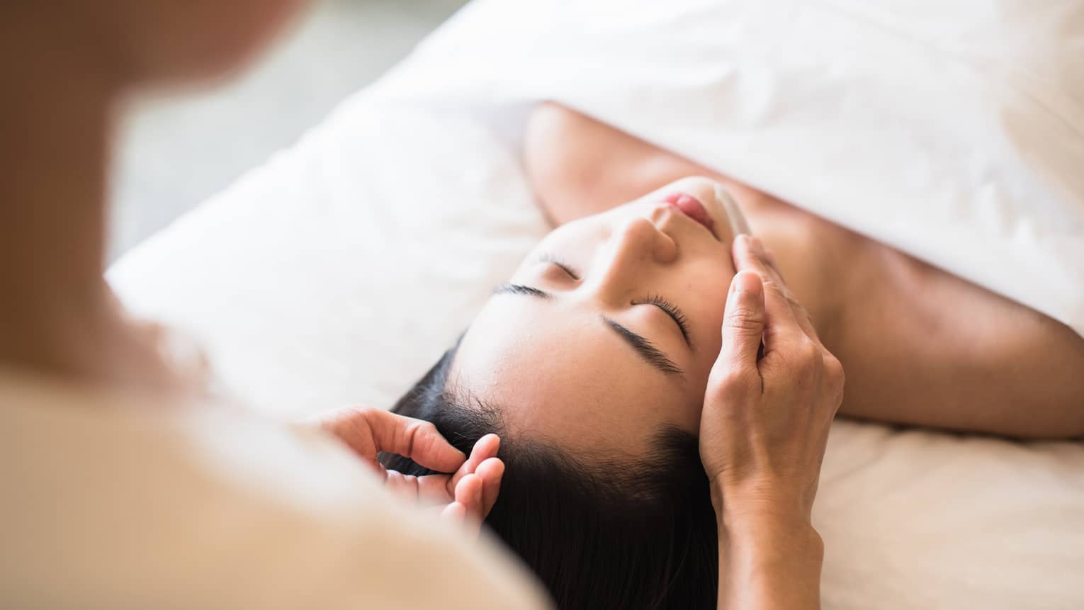A guest receiving a soothing facial at a spa, lying on a massage table, surrounded by calming décor and soft lighting.