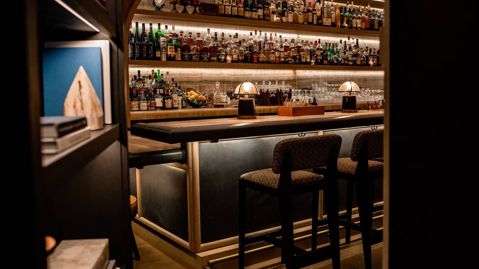 A bar with many bottles of liquor behind a bookcase.
