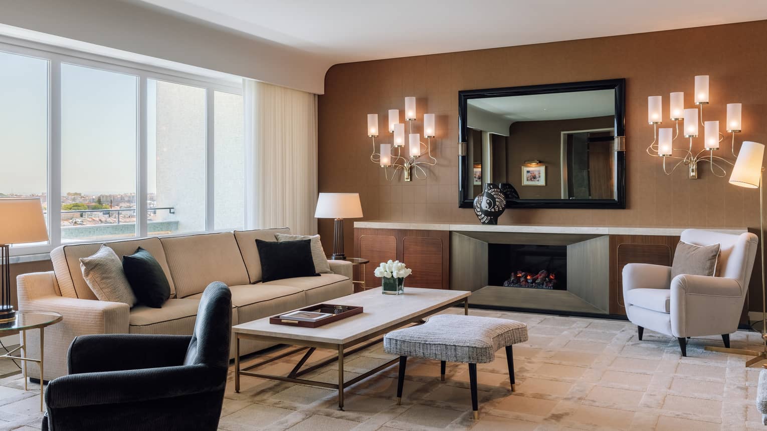 Living room with cream sofa, white arm chair, black arm chair, wall schones, brown accent wall