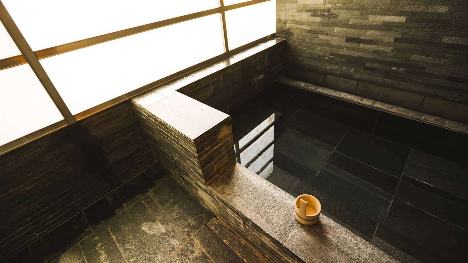 Rectangular black granite spa tub, small wood bowl on ledge