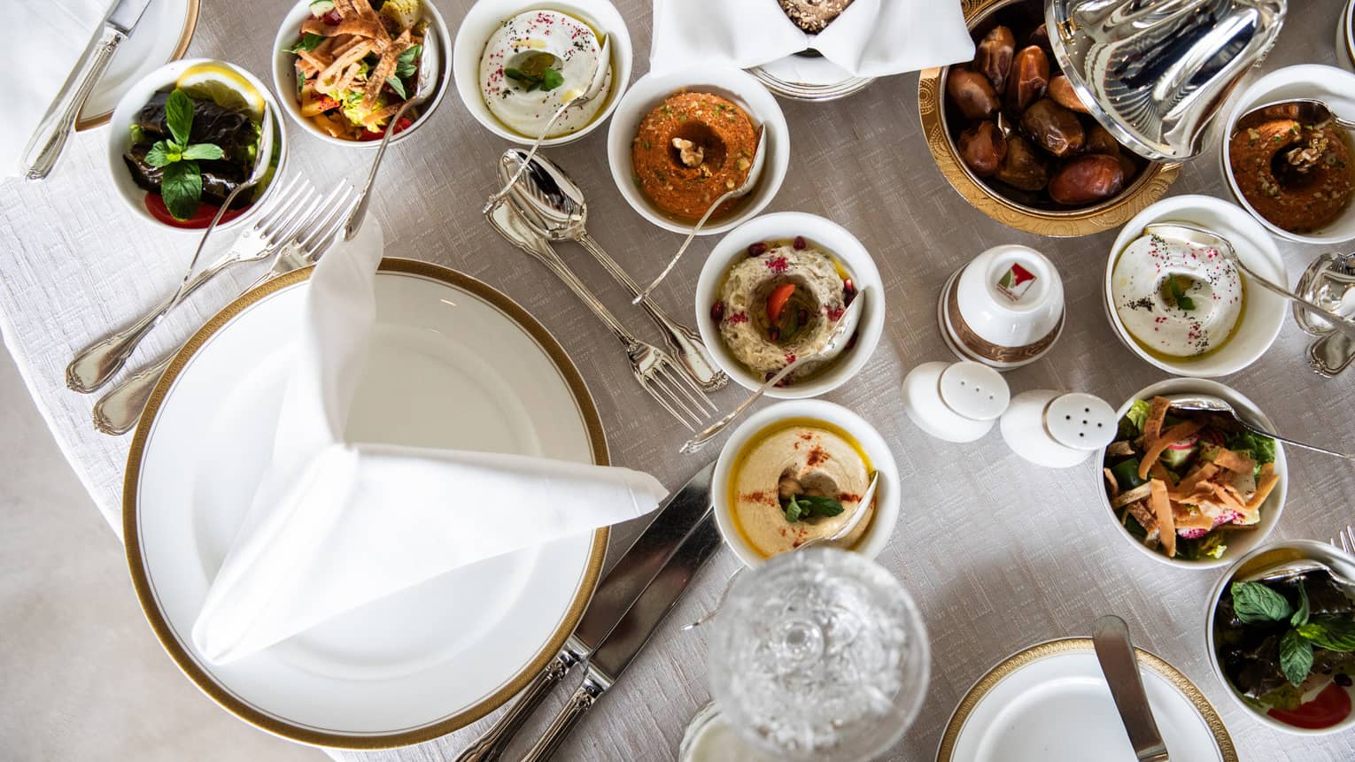 Aerial view of table with assorted Ramadan dishes in silver and ceramic dishes