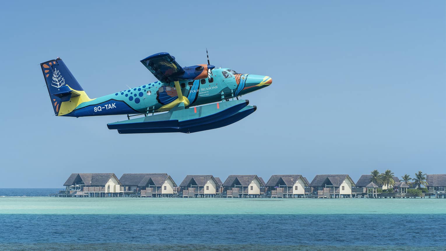 Maldives Sea Plane taking off with water villas and palm trees in the background