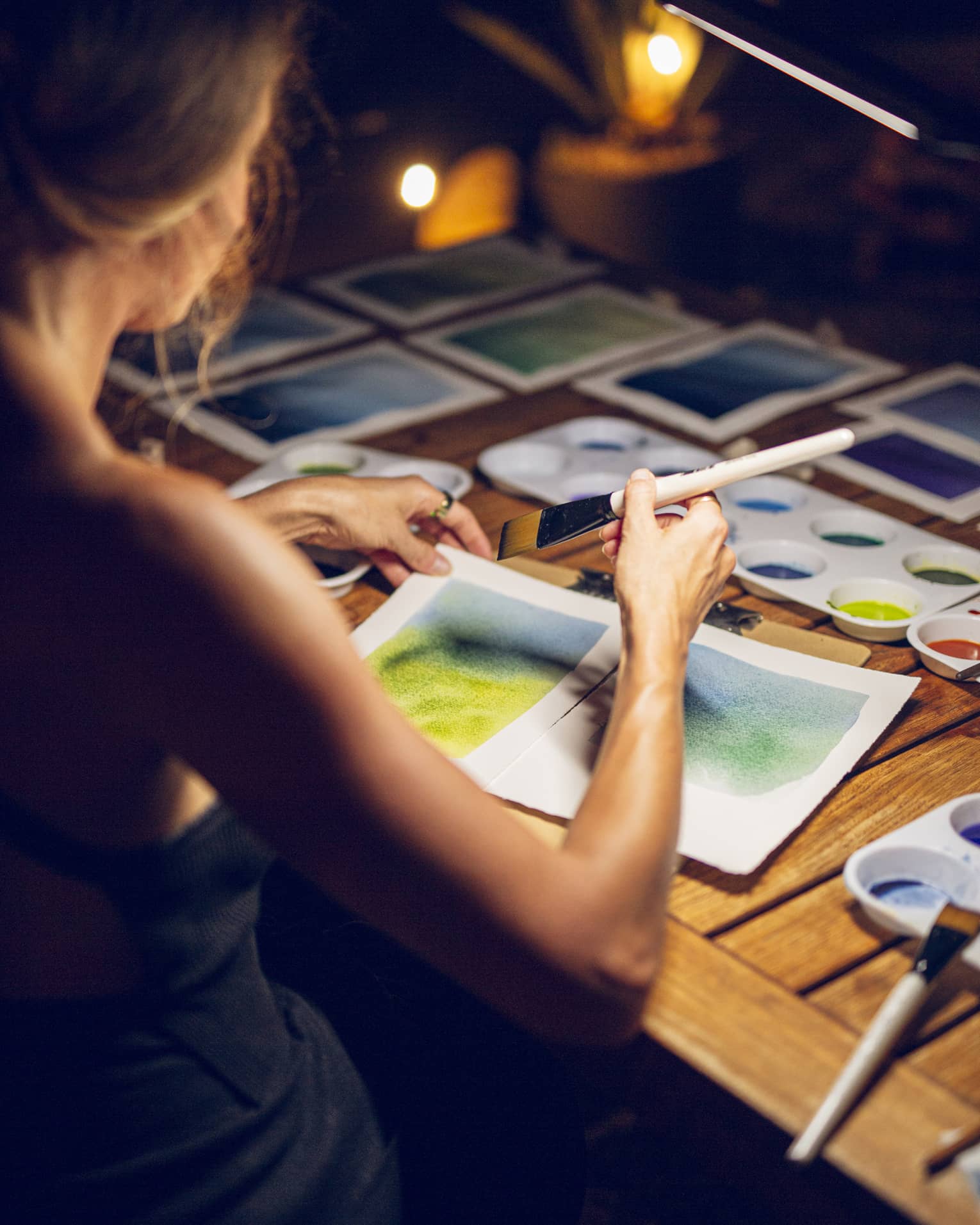 A woman painting a landscape on white paper with a brush