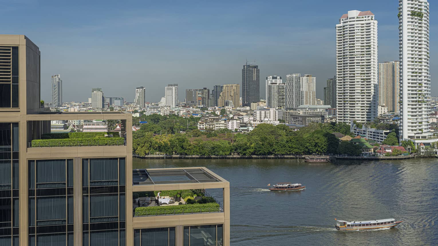 Hotel suites' outdoor patios, terraced on building, overlooking the Chao Phraya River and city