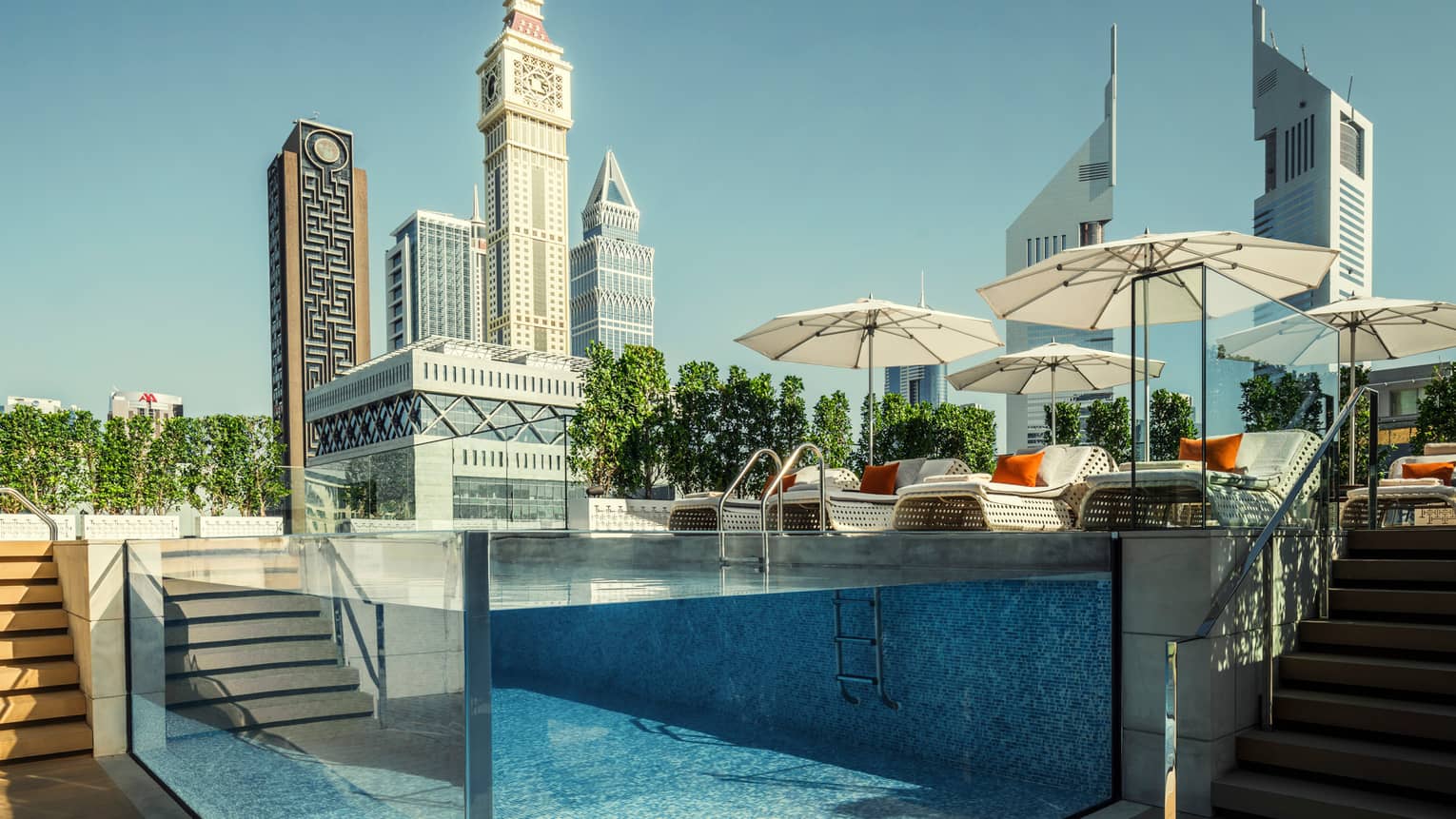 Raised glass plunge pool by stairs on patio deck, lounge chairs, umbrella