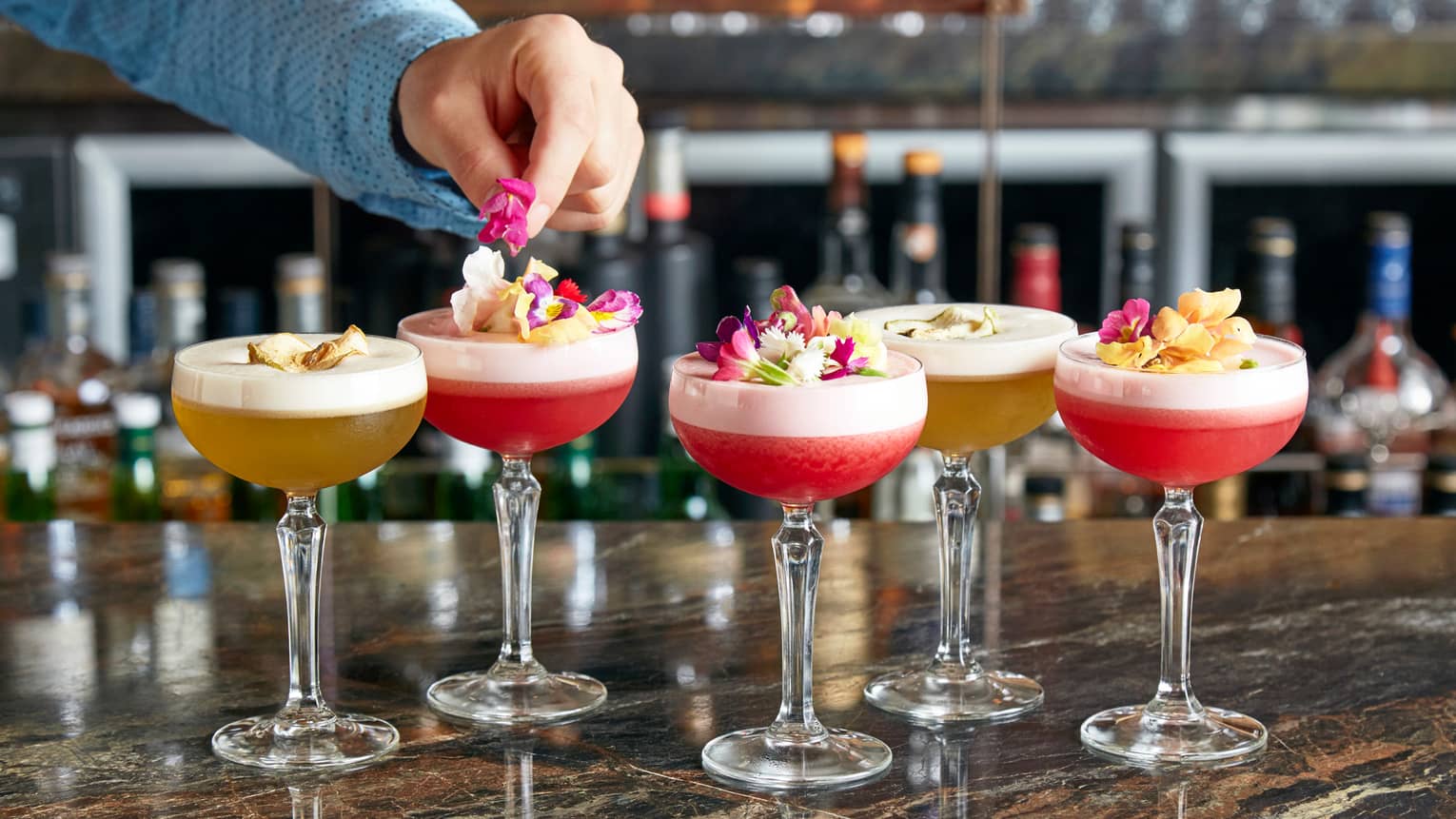 Grain bar mixologist garnishes colourful frozen cocktails with fresh flower petals