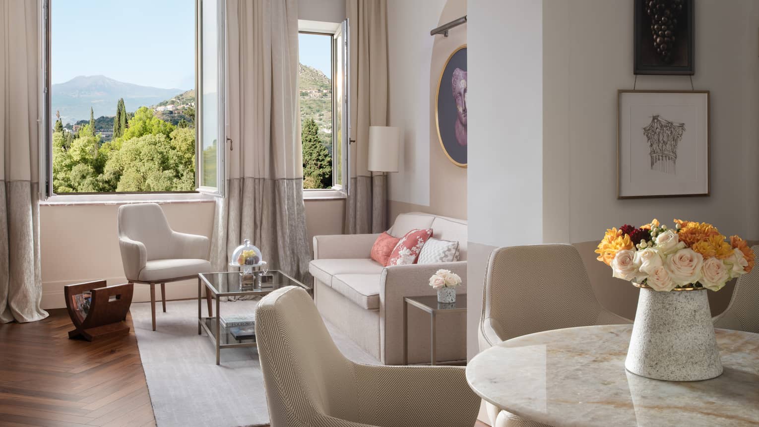 Round marble dining table, leather chairs, opening to living room with window
