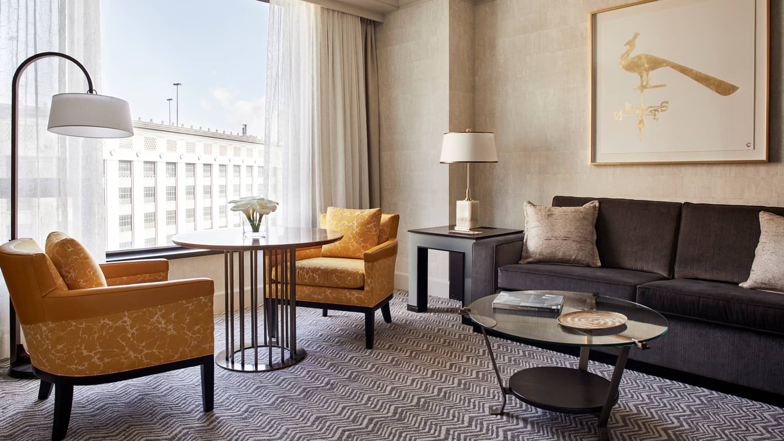 Superior Room living area with two yellow fabric armchairs around round cafe table in front of window, grey sofa