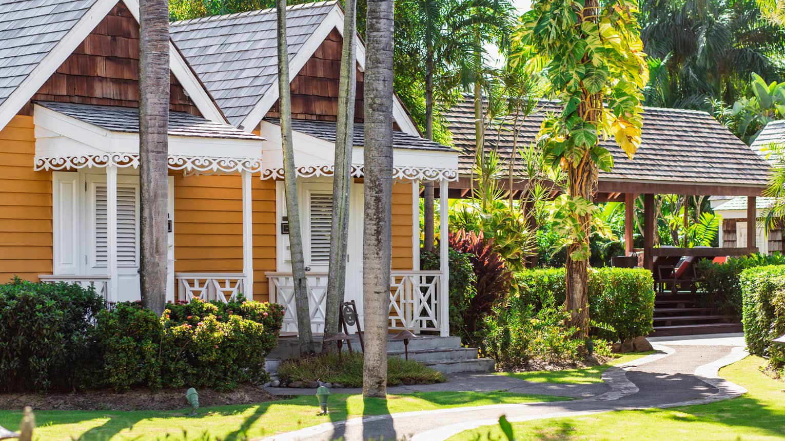 A small wooden building on a path surrounded by palm trees and plants.