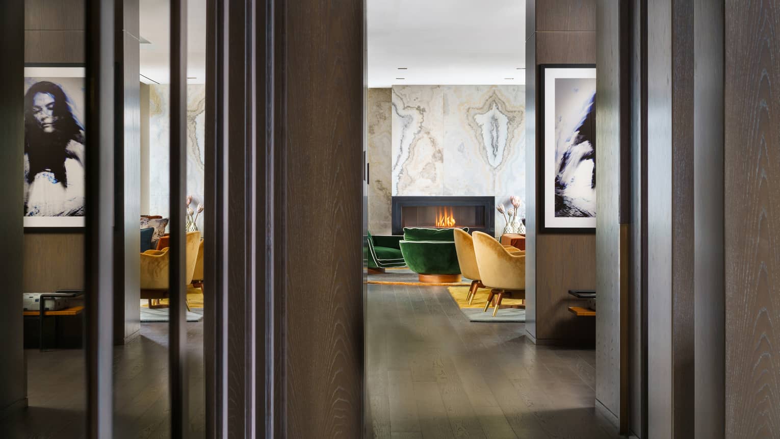 Entryway to suite, dark wood floors, mustard- and emerald green-coloured arm chairs by fireplace