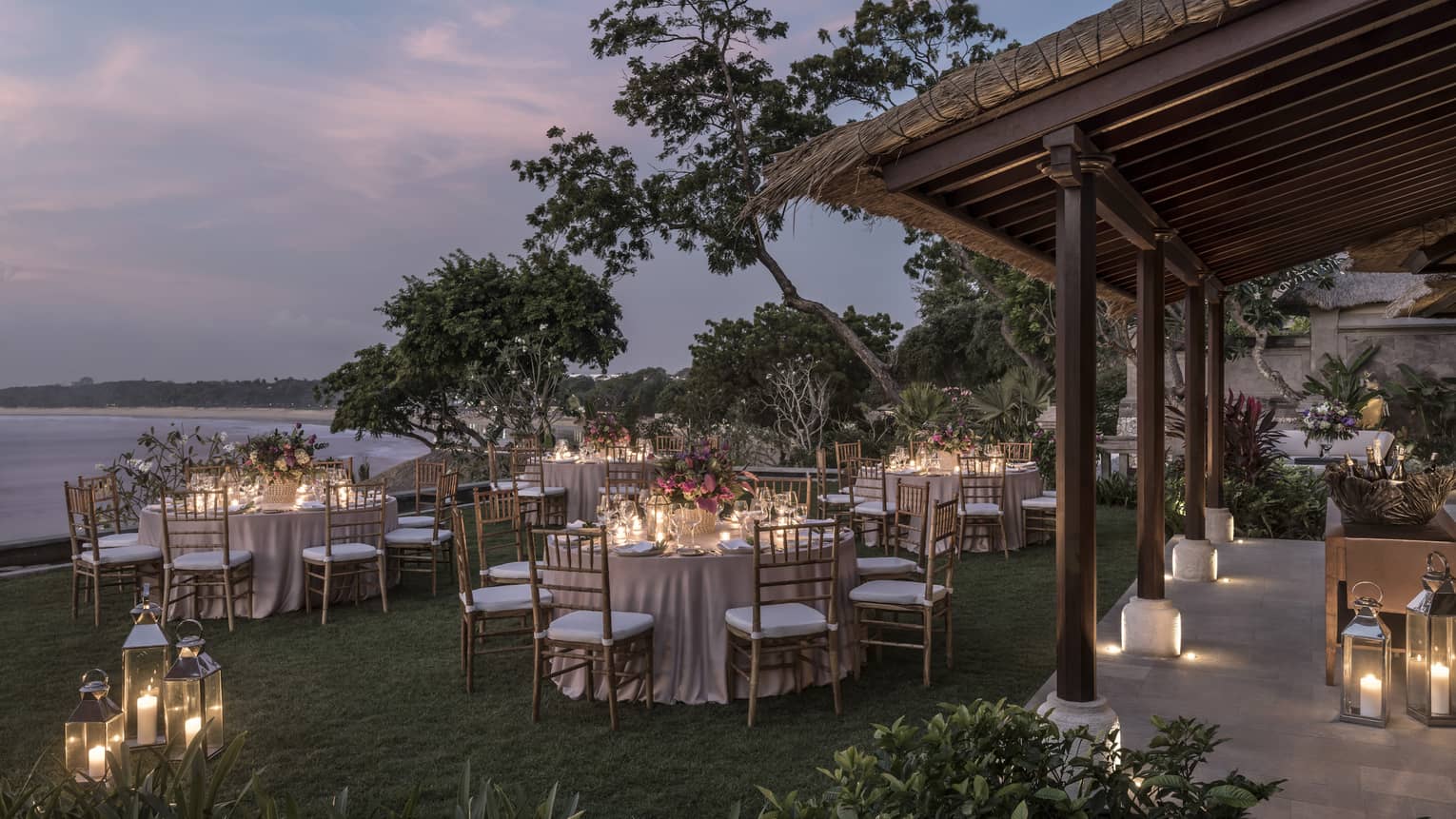 Small round dining tables with glowing candles on Imperial Villa lawn, patio