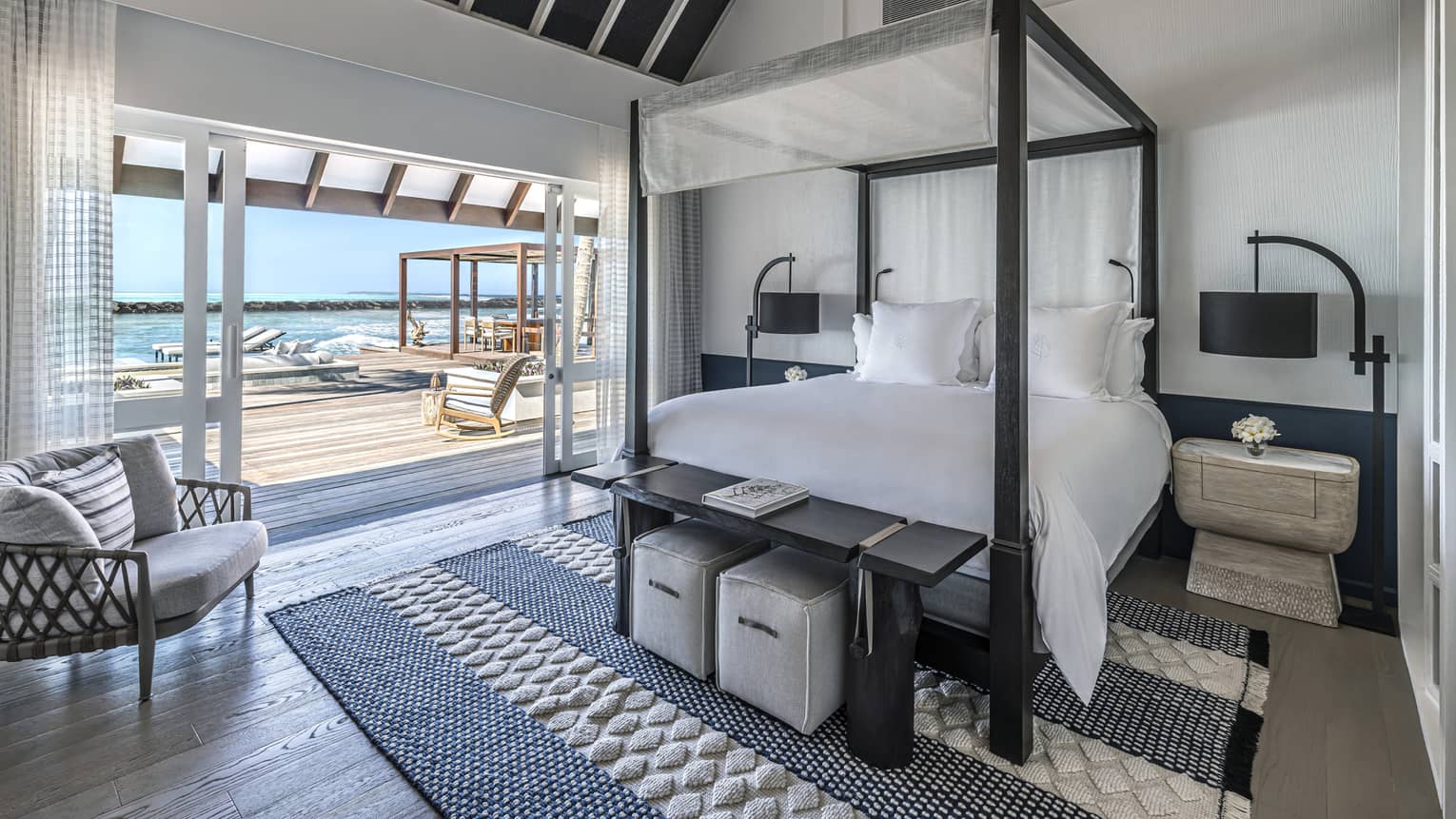Bedroom with four-poster bed, doorway opening on to deck with pool and cabana